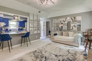A modern kitchen with blue cabinets, a bar area with stools, a living room with a sofa and decorative wall art, and a marble-patterned rug. - 9 Mi to Uptown Columbus! Family Home w/ Yard (Columbus)