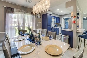 A dining area with a table set for four, a kitchen in the background, and a clock on the wall. - 9 Mi to Uptown Columbus! Family Home w/ Yard (Columbus)