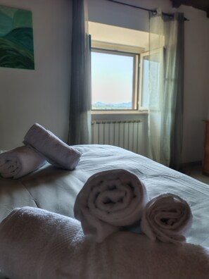A bed with rolled towels, a window with a view, and a curtain. - Your home in the historic center of Alatri - 2 bedrooms and 2 bathrooms - pets allowed (Alatri)
