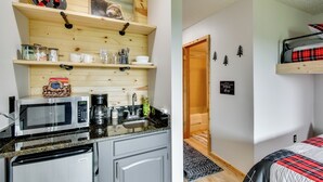 Uma cozinha com micro-ondas, cafeteira e armários, e um quarto com beliche e prateleira na parede.