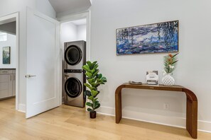 A room with a wooden console table, a potted plant, a painting, and a washing machine. - Walk to Shore! Family-Friendly Canyon Lake Retreat (Canyon Lake)