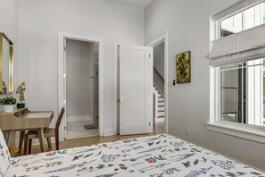 Ein Schlafzimmer mit Bett, Schreibtisch, Stuhl, Tür, Treppe und Fenster.