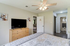 A bedroom with a bed, a dresser, a ceiling fan, a TV, and a door with a letter. - Great for Families! Schertz Getaway 6 Mi to Zoo (Schertz)