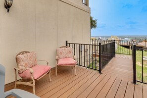 A wooden deck with two wicker chairs, a black metal railing, and a view of the ocean. - One-of-a-Kind Guest Suite in Hill Country w/ Pool (Bulverde)