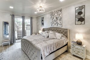 Une chambre à coucher avec un grand lit, une table de chevet, une lampe et des œuvres d’art accrochées aux murs.