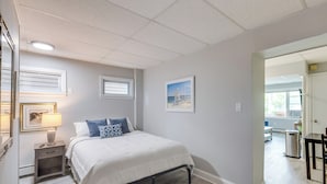 Ein Schlafzimmer mit einem Bett, einem Nachttisch, einer Lampe und einem gerahmten Bild an der Wand.