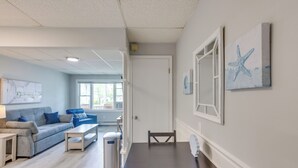 Ein modernes Wohnzimmer mit Sofa, Couchtisch und Esstisch. Ein Mülleimer und eine Tür zu einem anderen Raum sind ebenfalls vorhanden.
