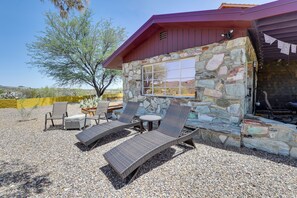 A patio with wicker furniture, a stone wall, and a view of the surrounding landscape. - Experience Staying in Geodome, Pool, Hot Tub, BBQ (Tucson)