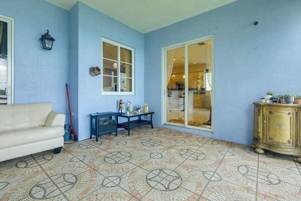 Una habitación con piso estampado, un sofá blanco, una mesa con objetos decorativos y un armario.