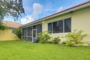 A single-story house with a screened porch, a small front yard, and a clear sky. - Trails & Resort Perks! Home in Royal Palm Beach (Royal Palm Beach)