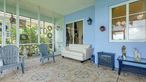 A room with a patterned floor, a white sofa, two chairs, a small table with decorative items, and a window with curtains. - Trails & Resort Perks! Home in Royal Palm Beach (Royal Palm Beach)