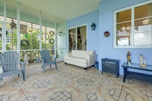 A room with a patterned floor, a white sofa, two chairs, a small table with decorative items, and a window with curtains. - Trails & Resort Perks! Home in Royal Palm Beach (Royal Palm Beach)
