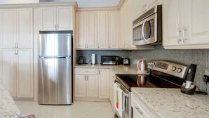 A modern kitchen with stainless steel appliances, light-colored cabinetry, and a tiled backsplash. - Trails & Resort Perks! Home in Royal Palm Beach (Royal Palm Beach)