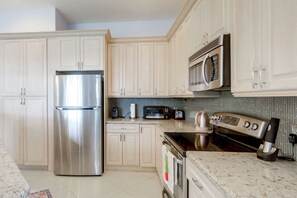 A modern kitchen with stainless steel appliances, light-colored cabinetry, and a tiled backsplash. - Trails & Resort Perks! Home in Royal Palm Beach (Royal Palm Beach)