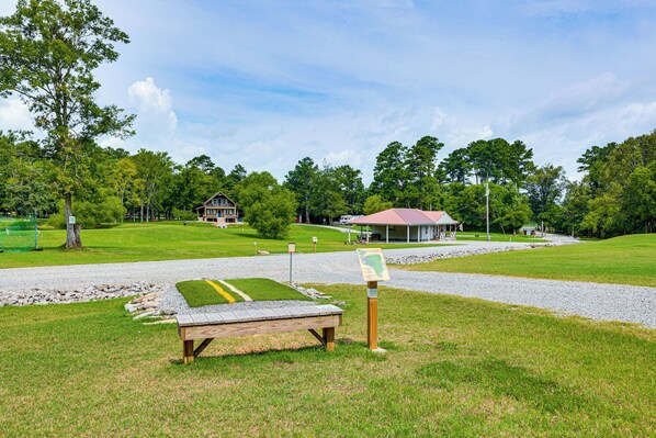 A grassy area with a wooden bench, a gazebo, and a house in the background. - The Hunter's Retreat at Kudzu Cove Cabins Resort (Guntersville)
