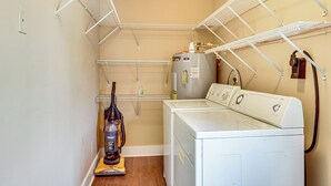 A laundry room with a washing machine, dryer, and a vacuum cleaner. - The Hunter's Retreat at Kudzu Cove Cabins Resort (Guntersville)