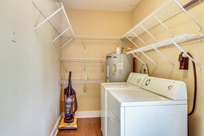 A laundry room with a washing machine, dryer, and a vacuum cleaner. - The Hunter's Retreat at Kudzu Cove Cabins Resort (Guntersville)