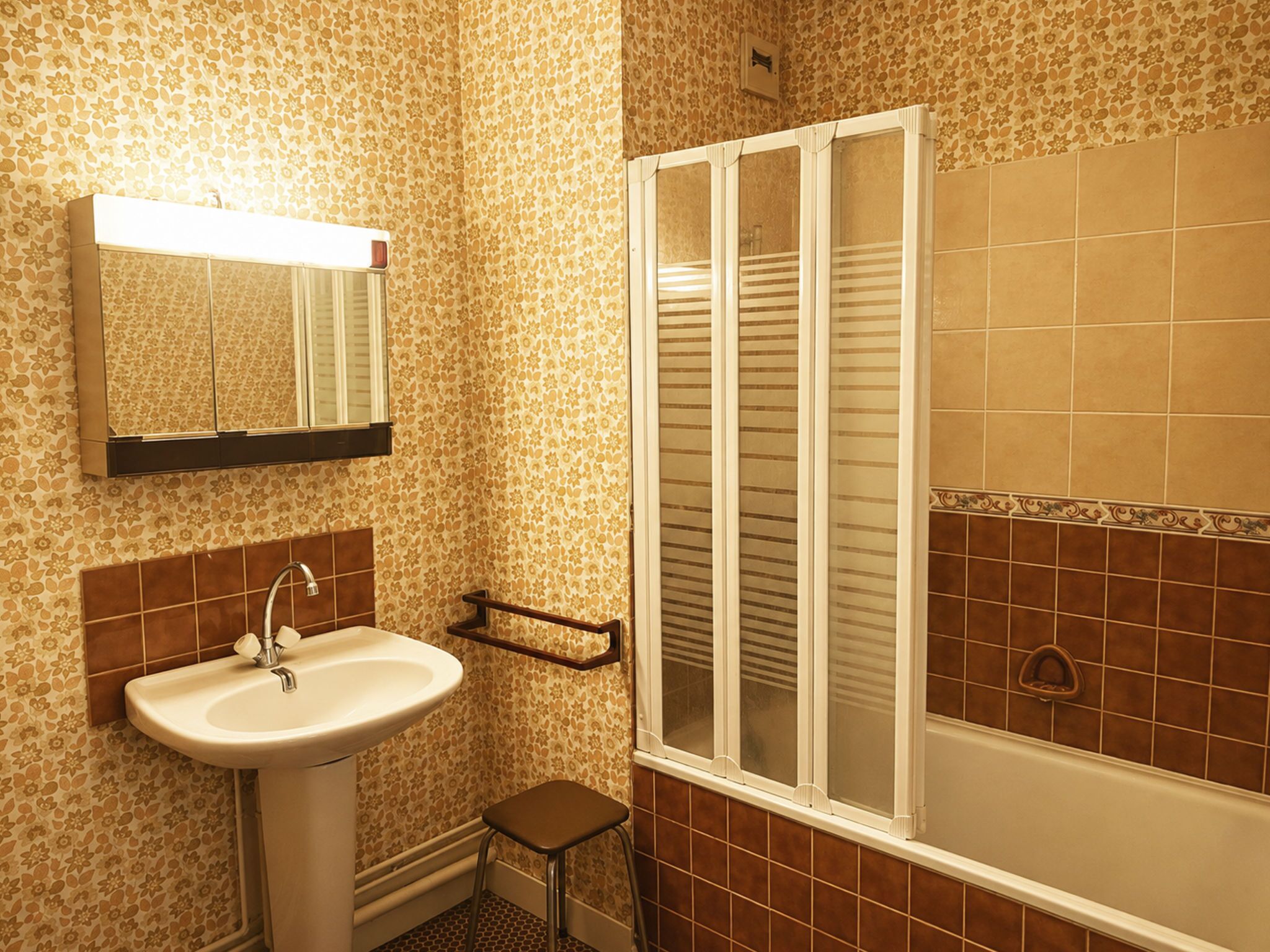 A bathroom with a sink, mirror, and a window with blinds.