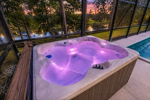 Ein Whirlpool mit Blick auf einen Pool und Bäume im Hintergrund.