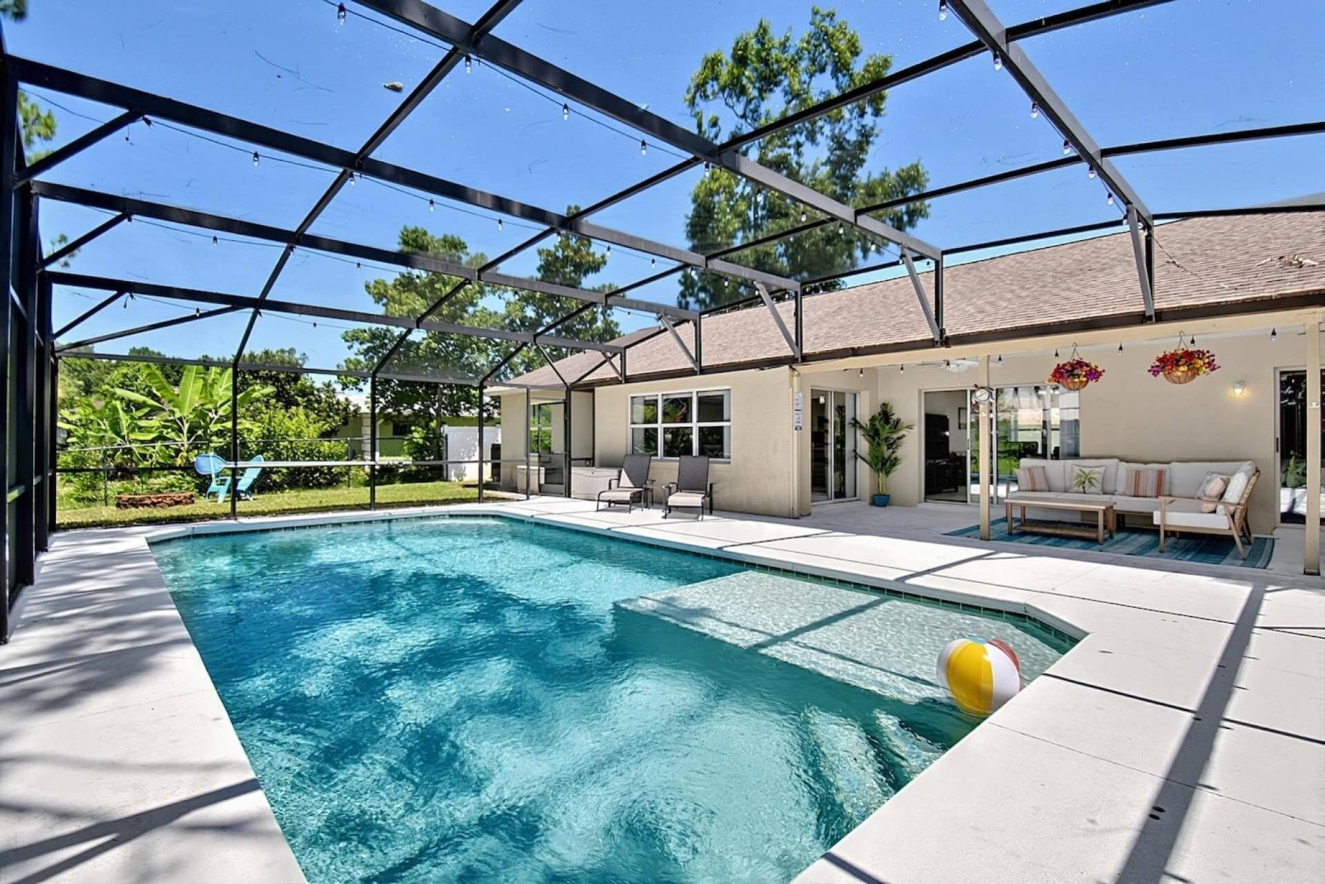 A covered swimming pool with lounge chairs and a patio area.