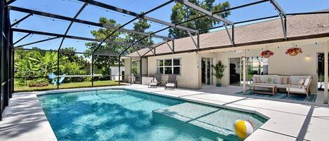 A covered swimming pool with lounge chairs and a patio area.
