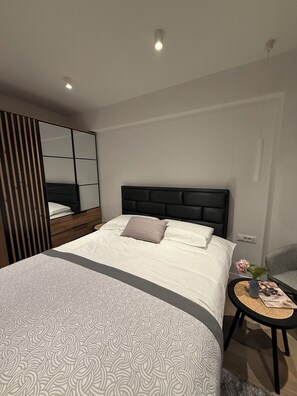 A modern bedroom with a large bed, a bedside table with a vase, and a mirror. - Just perfect St.Jacob apartment  (Dubrovnik)