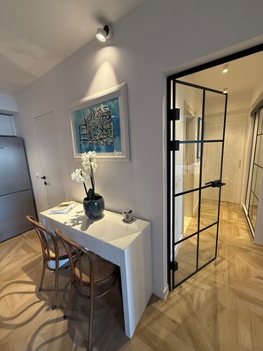 A modern kitchen with a white countertop, a wooden chair, a vase with flowers, and a framed artwork on the wall. - Just perfect St.Jacob apartment  (Dubrovnik)