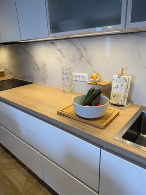 A kitchen with a marble backsplash, a wooden countertop, a bowl with vegetables, a glass pitcher, and a paper towel holder. - Just perfect St.Jacob apartment  (Dubrovnik)