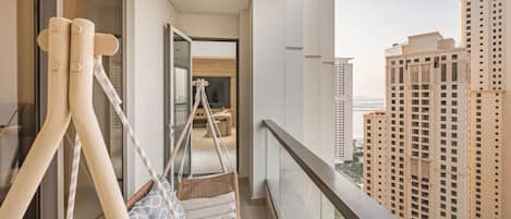 A balcony with a hanging chair, a view of tall buildings, and a glimpse of the interior.
