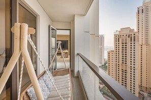 A balcony with a hanging chair, a view of tall buildings, and a glimpse of the interior. - FIRST CLASS |2BR| Marina Views | Near JBR Beach (JBR)
