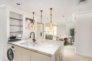 A modern kitchen with a marble countertop, a built-in washing machine, and pendant lighting. - FIRST CLASS |2BR| Marina Views | Near JBR Beach (JBR)