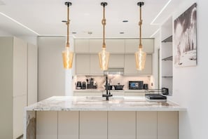 A modern kitchen with a marble island, pendant lights, and a microwave. - FIRST CLASS |2BR| Marina Views | Near JBR Beach (JBR)