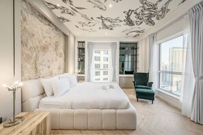 A modern bedroom with a large bed, a green armchair, a large window with a city view, and a ceiling with fish decals. - FIRST CLASS |2BR| Marina Views | Near JBR Beach (JBR)
