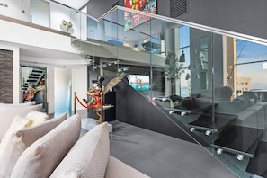 A modern interior with a glass staircase, a statue, and a view of the city. - FIRST CLASS |3BR| Luxury Duplex w/ Ain Dubai View (JBR)