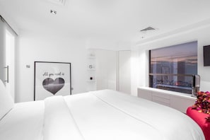 A modern bedroom with a large bed, a window with a city view, a wall-mounted TV, and a framed inspirational quote. - FIRST CLASS |3BR| Luxury Duplex w/ Ain Dubai View (JBR)
