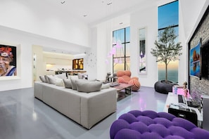 A modern living room with a grey sofa, a striped armchair, and a purple pouf. - FIRST CLASS |3BR| Luxury Duplex w/ Ain Dubai View (JBR)