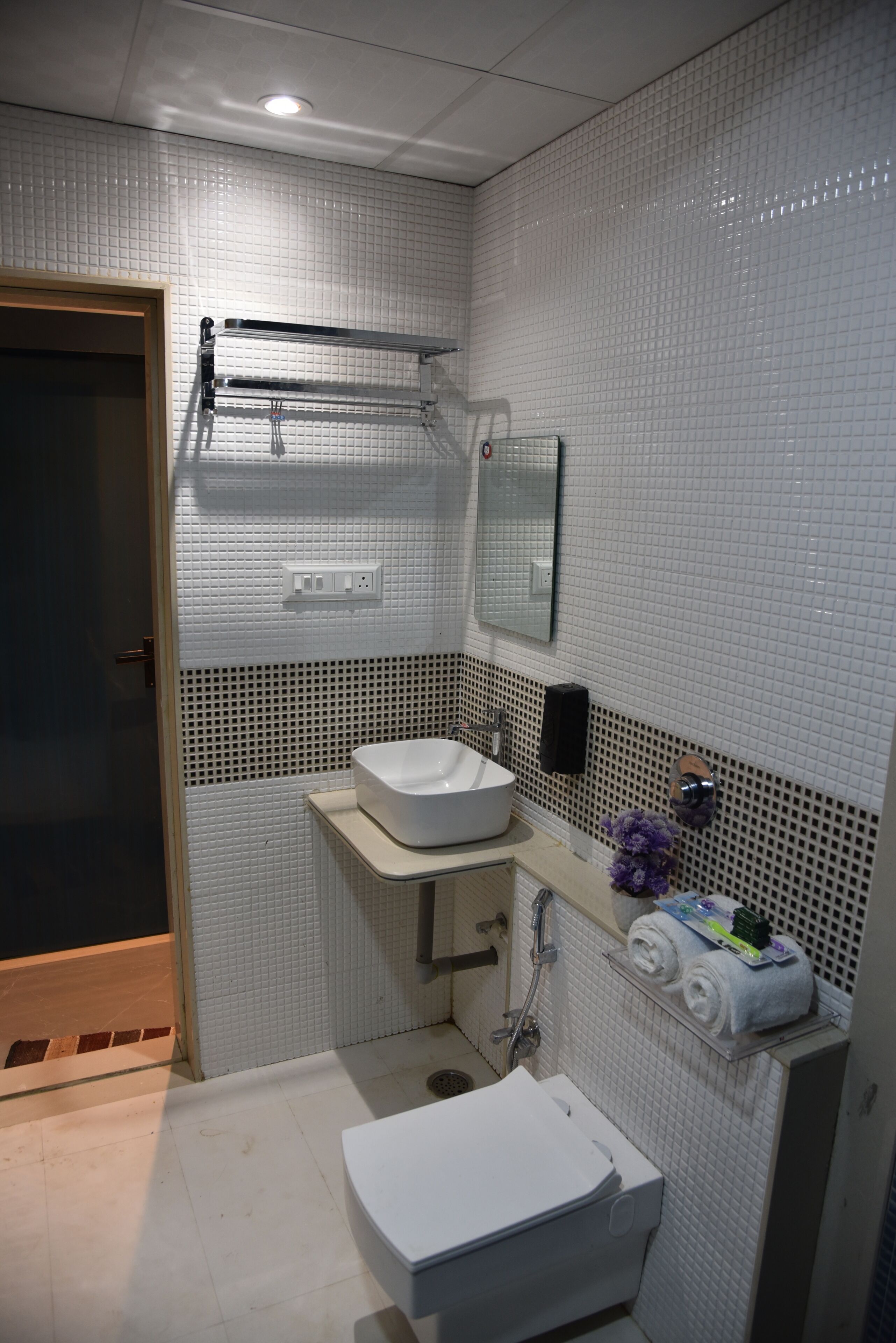 A bathroom with a white sink, a mirror, a towel rack, and a shower area.