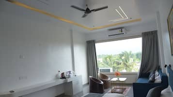 A modern hotel room with a bed, a desk, a chair, a ceiling fan, and a view of palm trees.