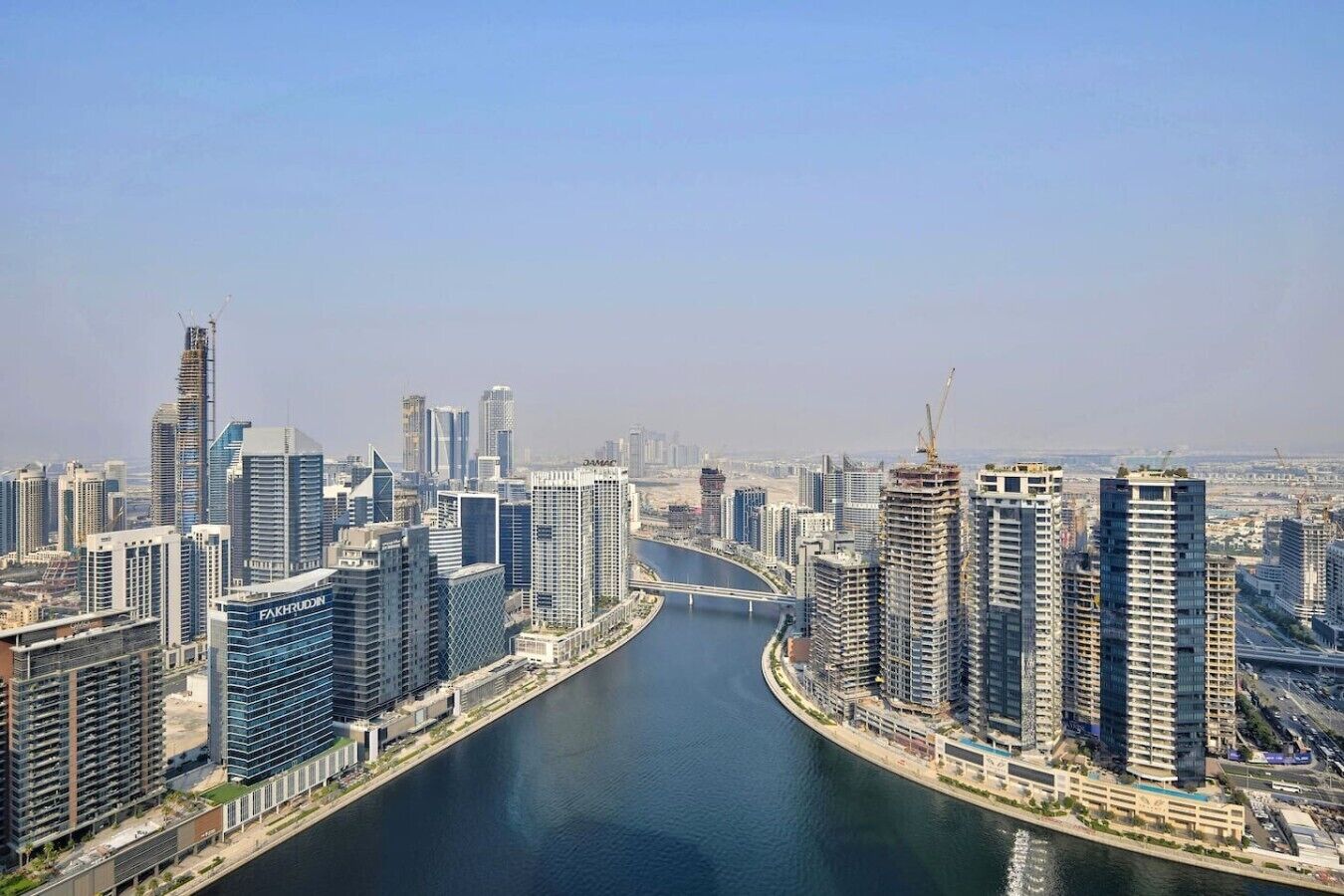 A cityscape with modern high-rise buildings, a river, and a bridge.