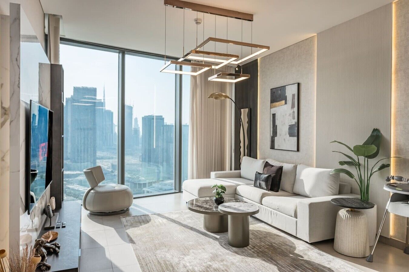 A modern living room with a large window, a sofa, a coffee table, and a TV.