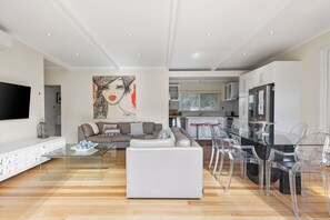 Ein modernes Wohnzimmer mit einem Glastisch, einem weißen Sofa und einem Gemälde an der Wand.