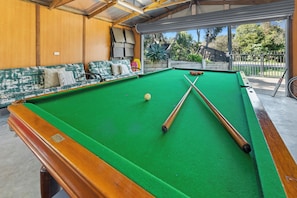 A pool table with a green felt surface, two pool cues, and a cue ball. - Bella Rye by Ready Set Stay (Rye)