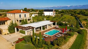 A large house with a pool, outdoor seating, and a view of mountains. - Stunning home in Zerava (Zerava)
