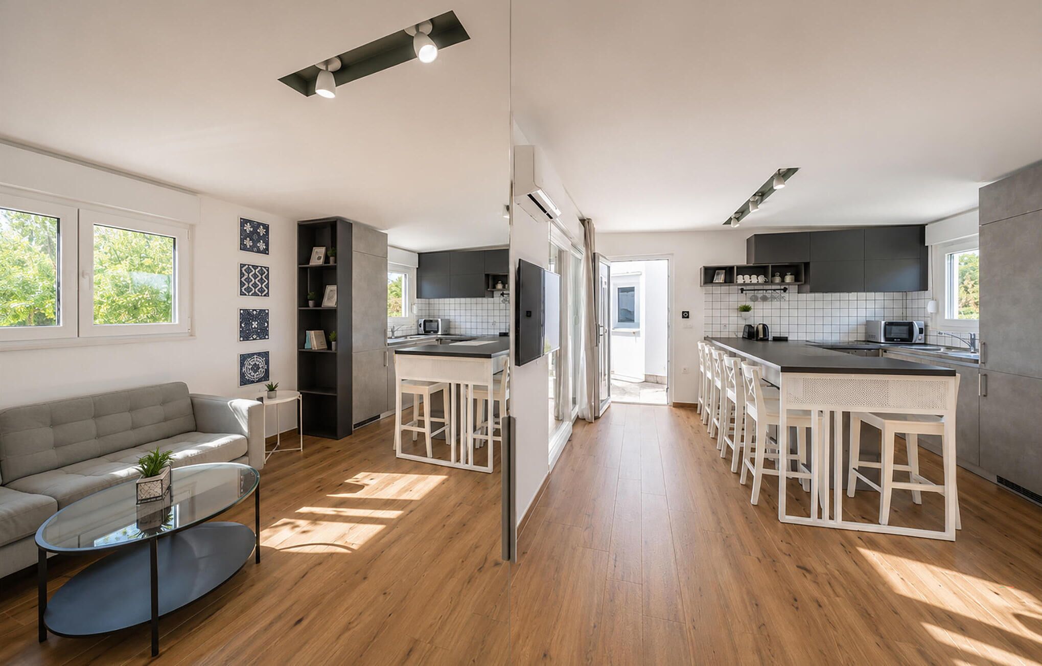 A modern kitchen with a central island, bar stools, and a built-in TV.