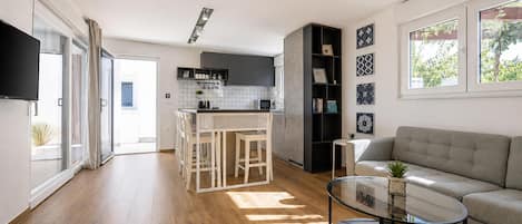 Eine moderne Küche mit einer zentralen Kochinsel, einem Essbereich mit Stühlen, einer Couch und einem Couchtisch.