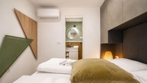 Een hotelkamer met een bed, een kussen, een airconditioner, een spiegel en een wandplank.
