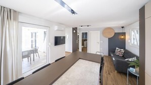 A modern living room with a sofa, a TV, and a dining area with a table and chairs. - Stunning home in Zerava (Zerava)