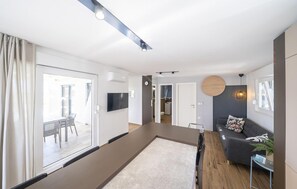 A modern living room with a sofa, a TV, and a dining area with a table and chairs. - Stunning home in Zerava (Zerava)