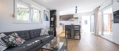 Una sala moderna con un sofá, una mesa de centro de cristal y una zona de cocina con una mesa de comedor y sillas.