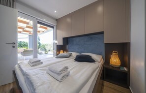 A modern bedroom with a large bed, a glass door leading to an outdoor area, and a nightstand with a lamp. - Stunning home in Zerava (Zerava)